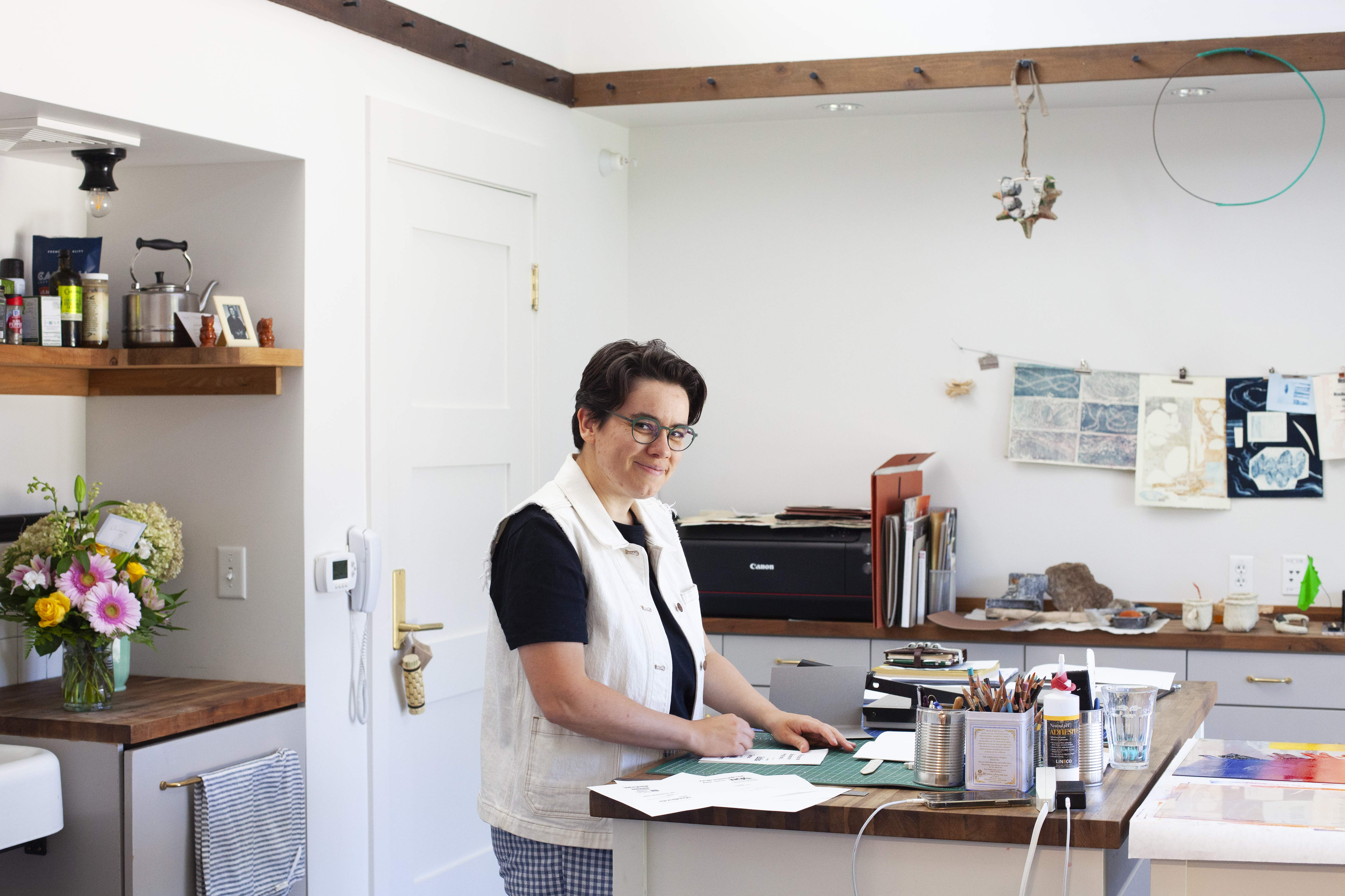 Person standing at kitchen island with art supplies at James Castle House. 