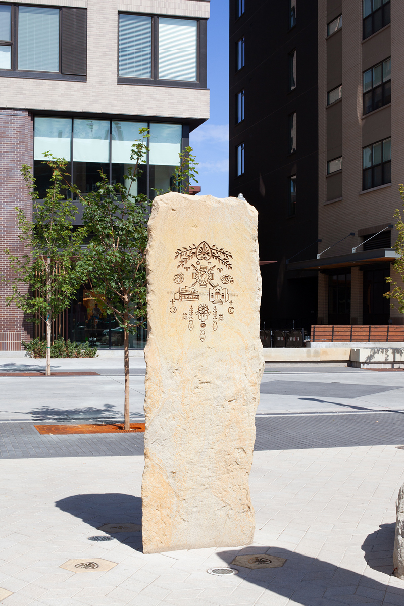 A sandstone pillar with an etching of Greek motifs and symbols.
