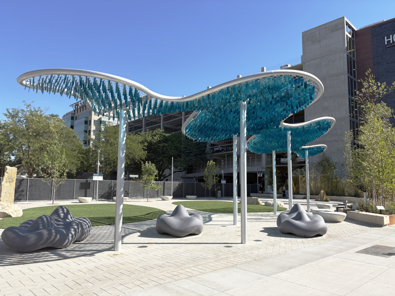 A shade canopy structure consisting of blue, alcohol painted flappers suspended in spanners set between stretched steel cables.