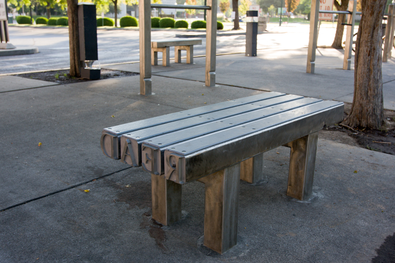 A stainless steel bench made from posts that look like letter blocks used in old printing presses.