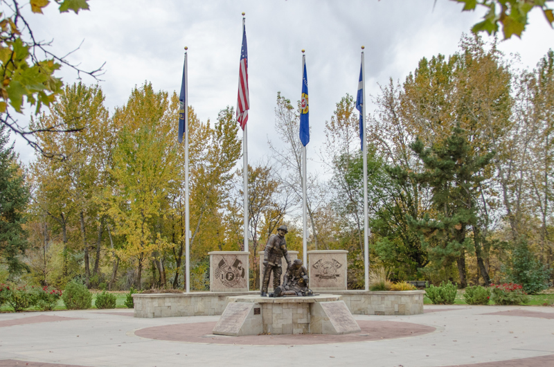 A life-sized bronze sculpture of three firefighters. One lies lifeless in the arms of another. The third stands beside them. 