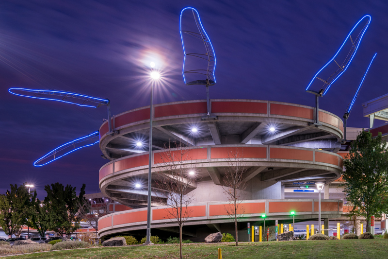 A series of 5 large blue neon light installations in the shape of a wing ascending the spiral ramp of the Boise Airport parking garage. 