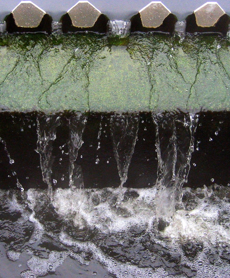 Water pouring through a toothed grate meant to separate out unwanted materials.