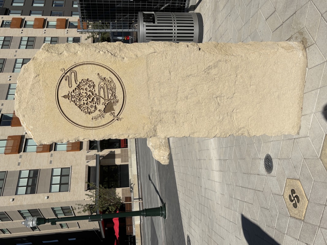 A sandstone pillar with an etching of a leaf made of various motifs and symbols meant to represent all other immigrant cultures not explicitly depicted in the other ancestral pillars.