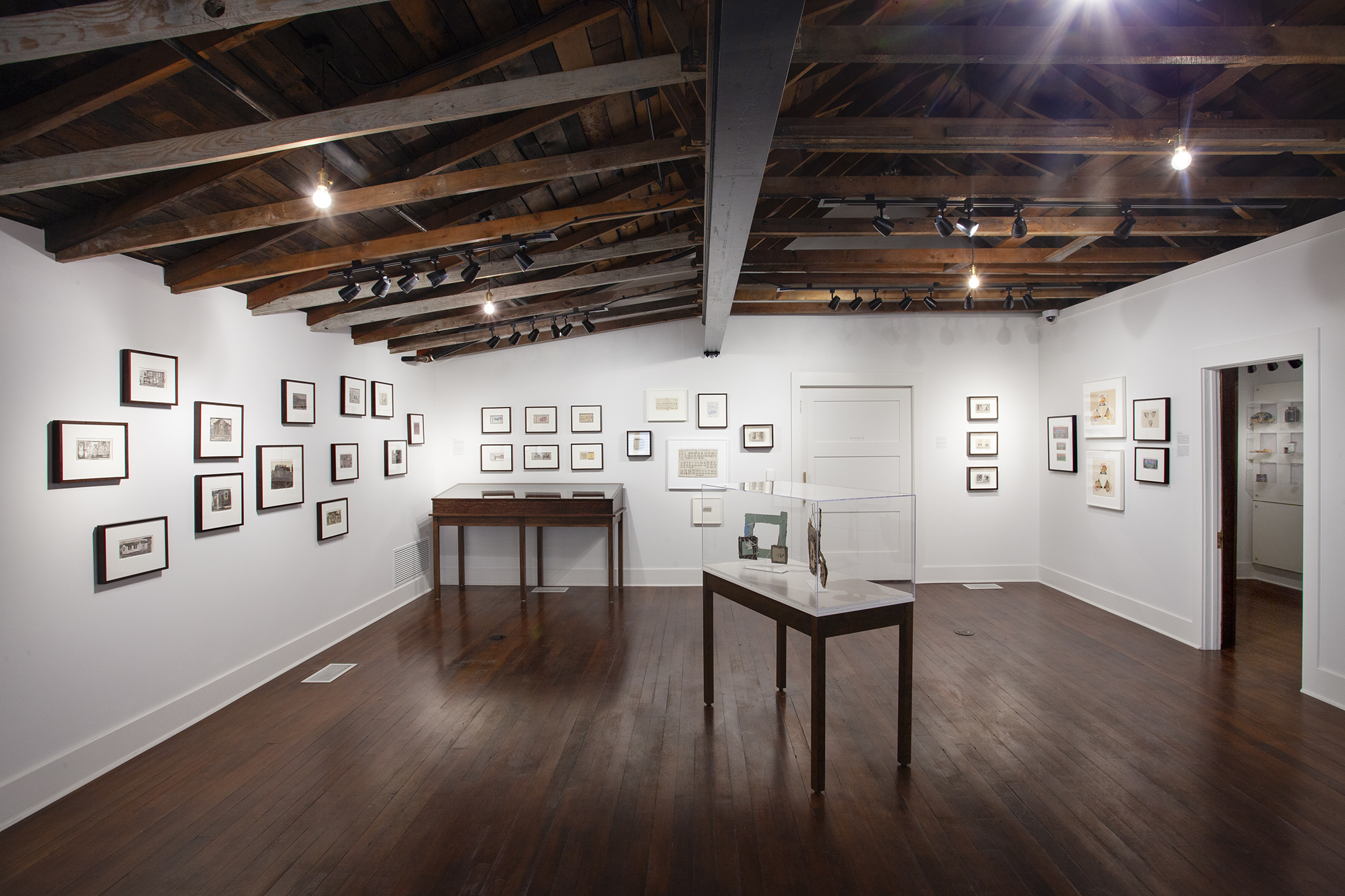 Exhibit area at James Castle House showing framed images on walls, and glass enclosed tables with artifacts.