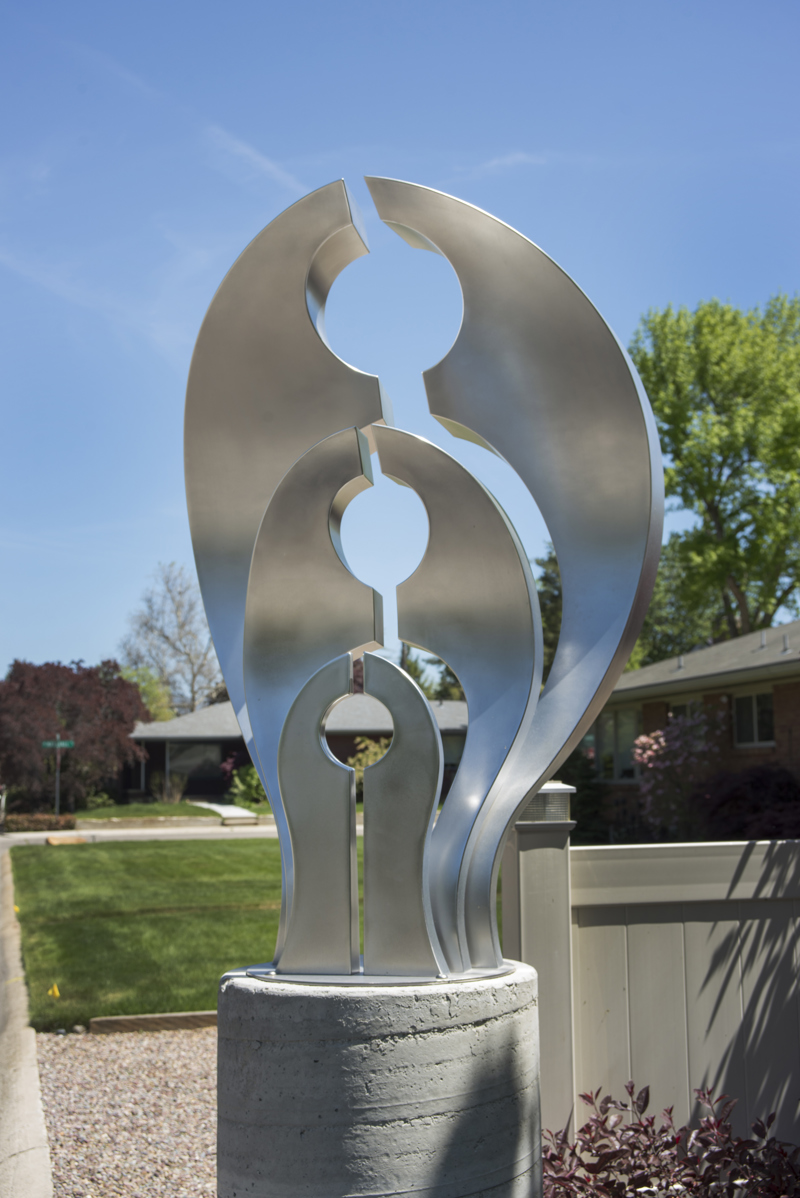 A medium abstract stainless steel sculpture on a concrete column. 