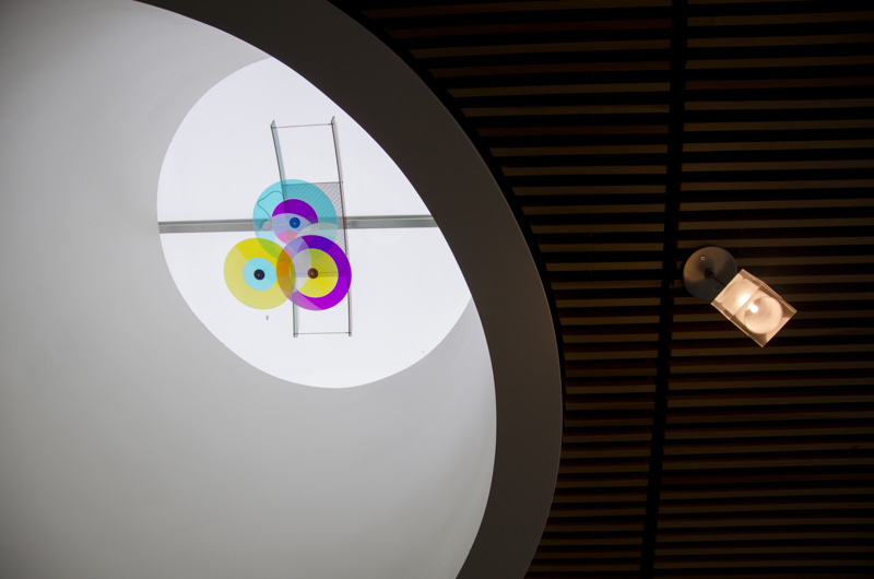 An mobile made of colorful acrylic installed in a skylight. 