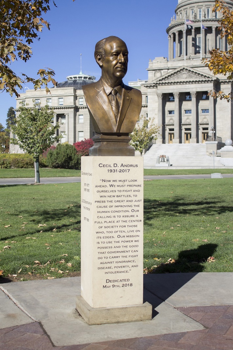 A bronze bust portrait of Cecil D. Andrus. The bust sits atop a sandstone pedestal on which is carved text that reads, "Cecil D Andrus. 1931-2017." After, follows a quote by Andrus which reads, "Now we must look ahead. We must prepare ourselves to fight and win new battles, to press the great and just cause of improving the human condition. Out calling is to assure a full place at the center of society for those who, too often, live on its edges. Our mission is to use the power we possess and th