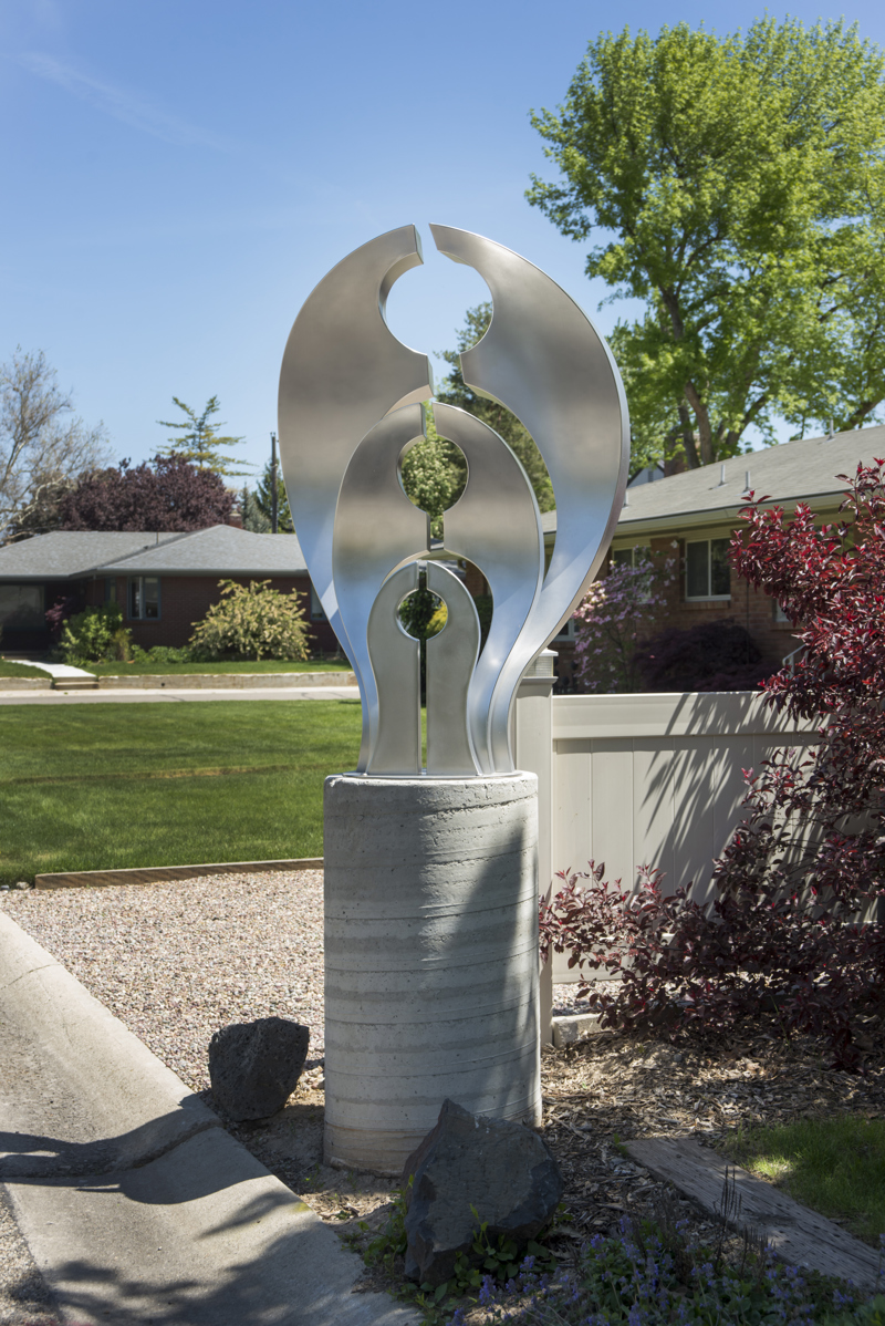 A medium abstract stainless steel sculpture on a concrete column. 