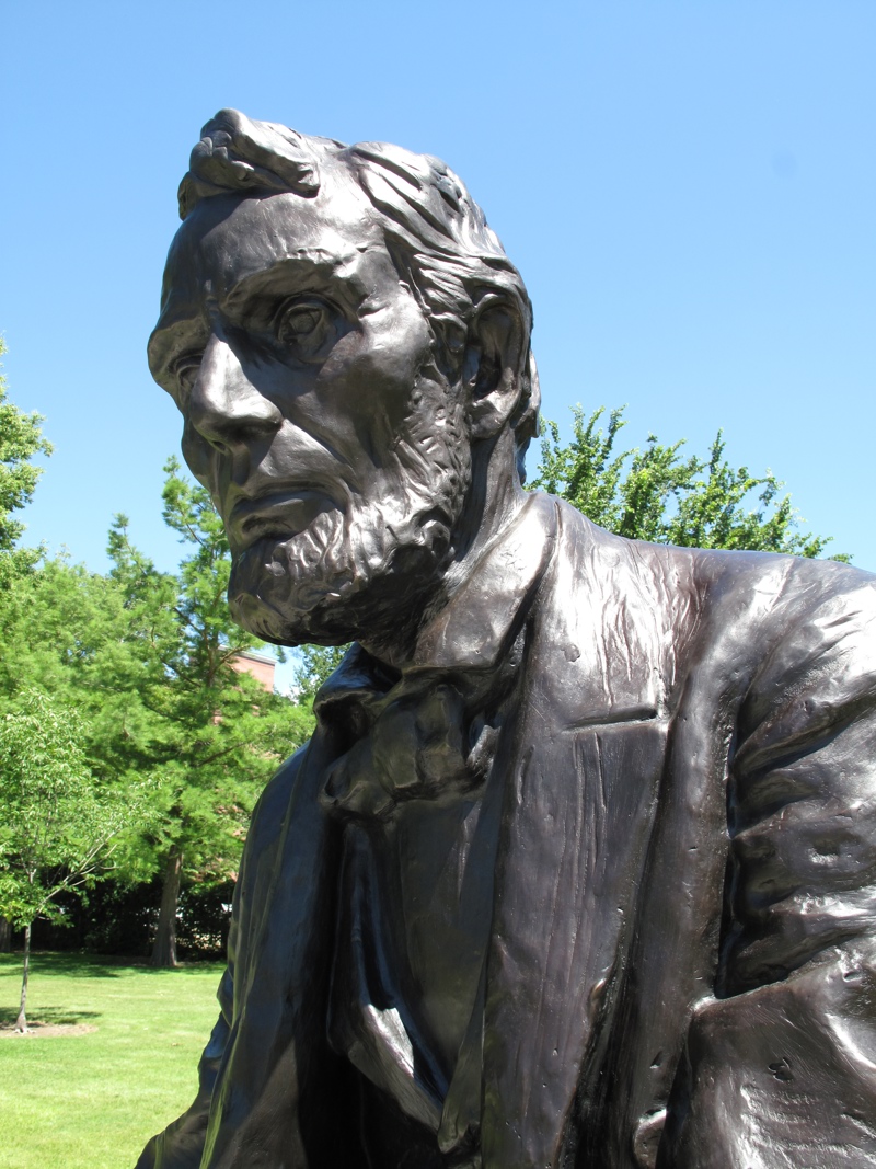 A facial closeup of a large bronze sculpture of President Lincoln.