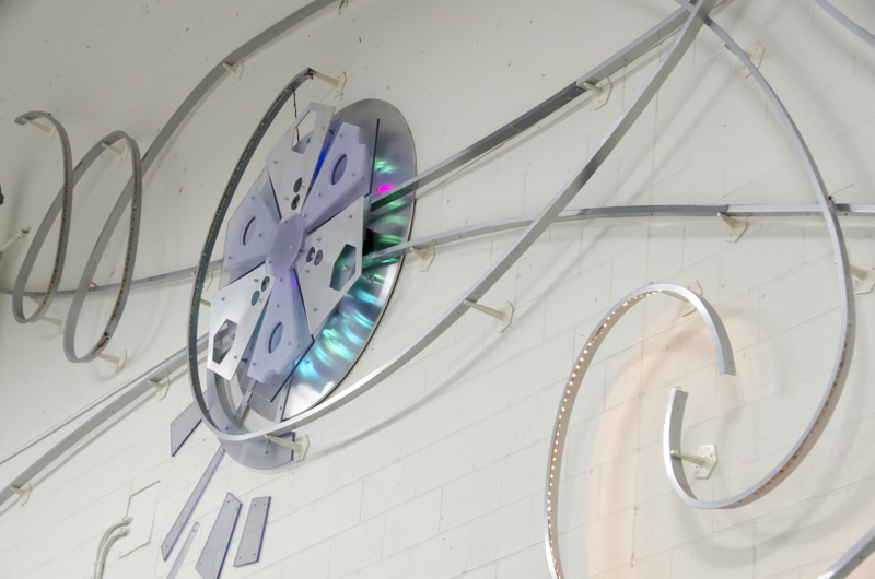 And abstract wall and light installation of curved metal strips and discs lined with color changing LED lights.