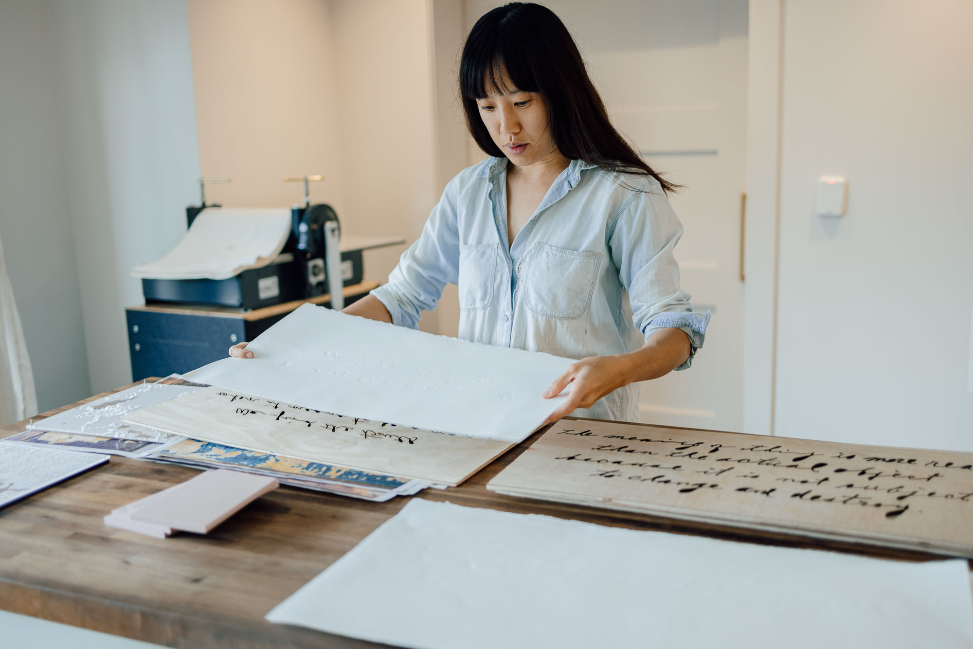 Resident working with large format paper with text print at countertop at James Castle House.