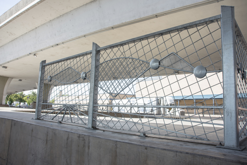 A decorative galvanized steel fence at the far end of a skate park.