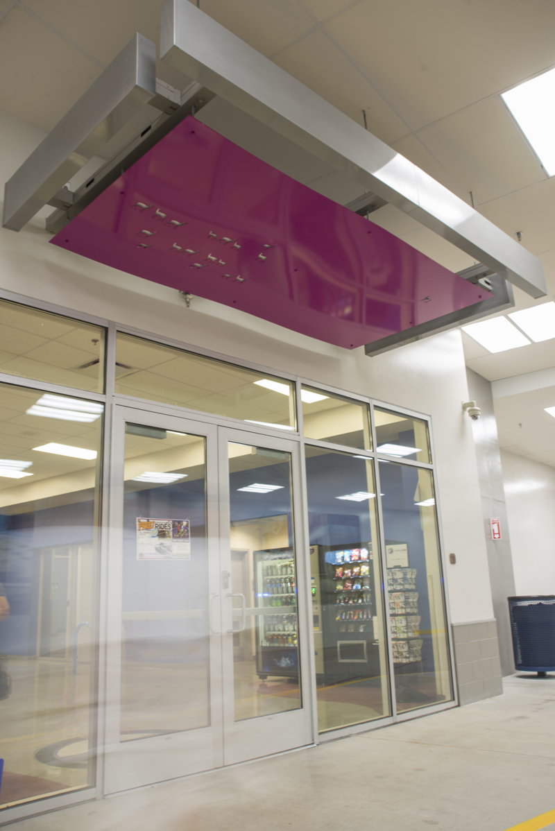 A doorway awning made of painted cut metal. In the awning, lit with backlighting, are holes in the shape of deer.