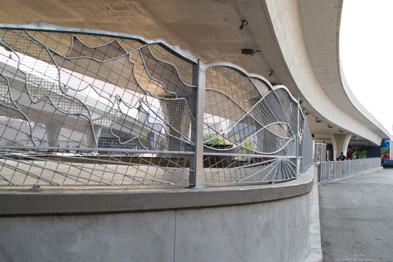 A decorative galvanized steel fence at the far end of a skate park.
