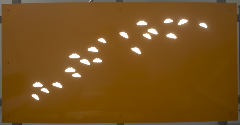 A doorway awning made of painted cut metal. In the awning, lit with backlighting, are holes in the shape of butterflies.