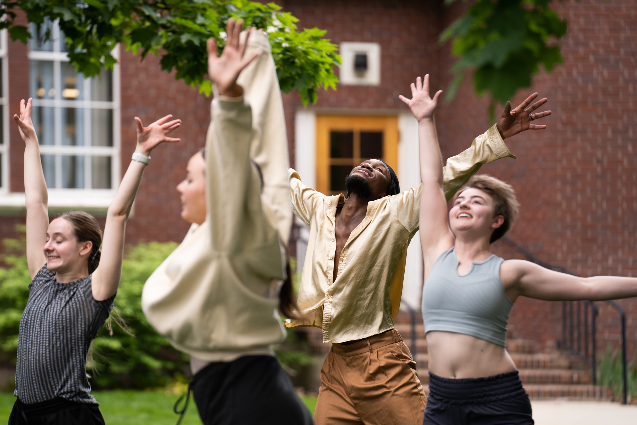 Dancers smile with arms raised in outdoor performance. 