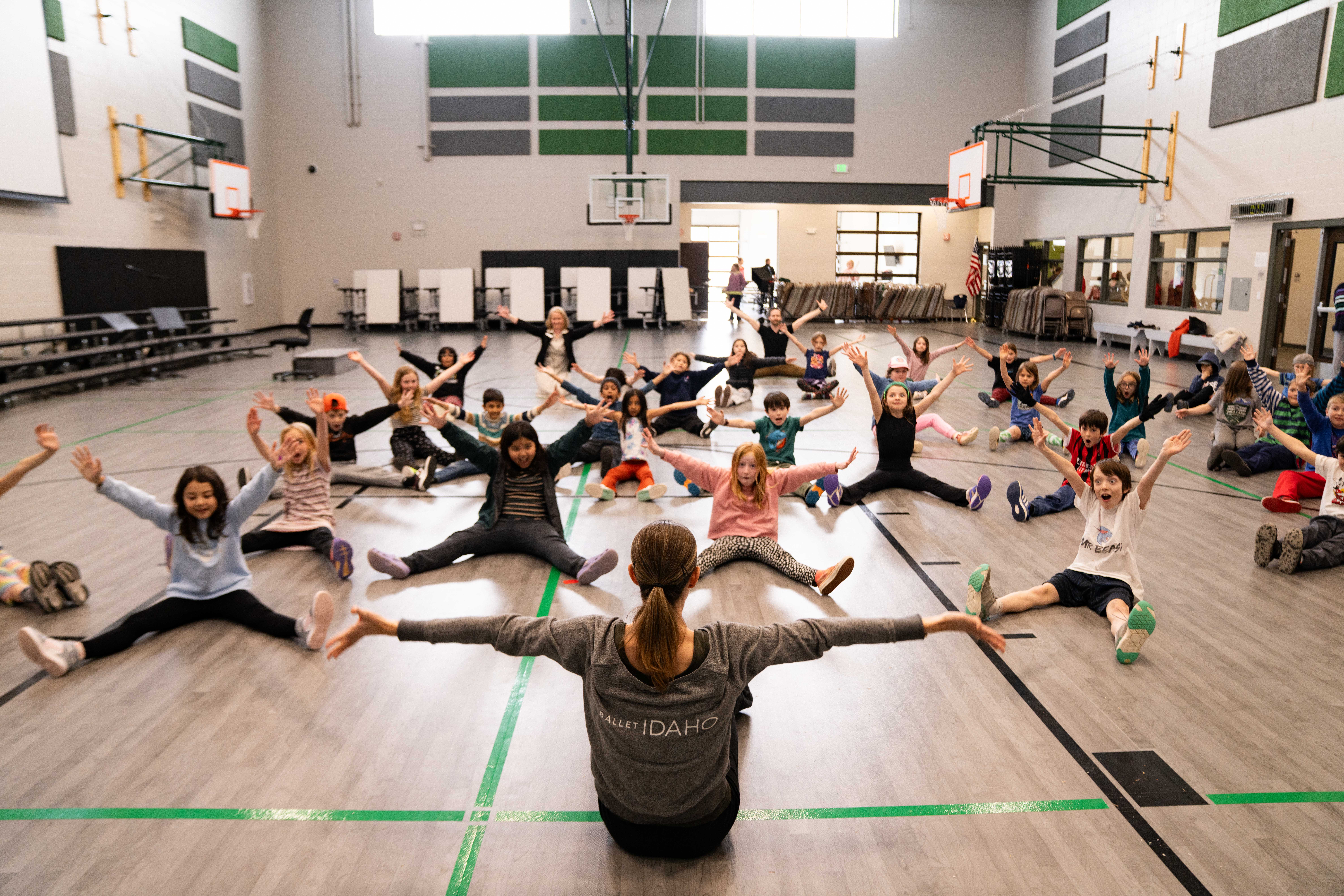 Children being led in stretching exercise in a gymnasium. 