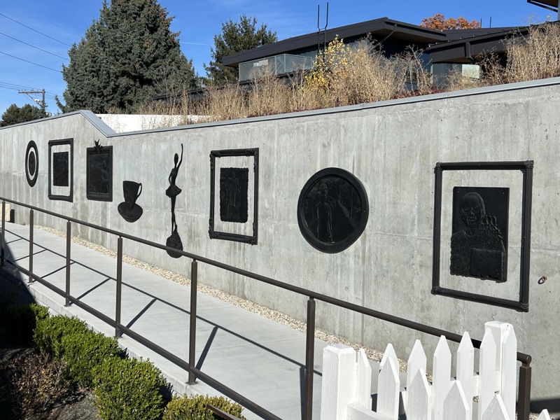A series of 8 cast bronze resin sculptures installed onto a cement wall. 